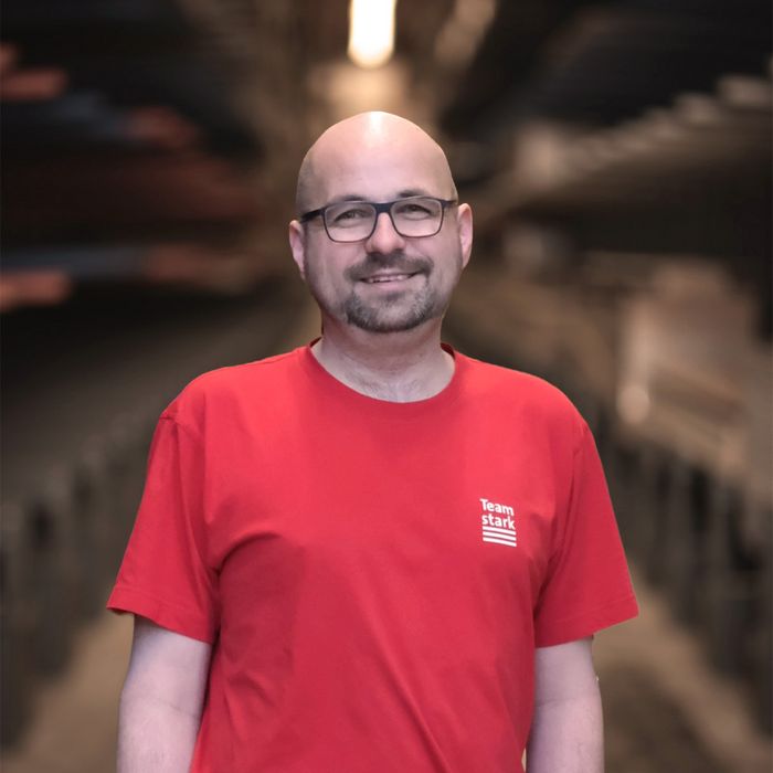 Stark AG Mitarbeiter Mitarbeiter von Stark AG in Lagerhalle in rotem Shirt.