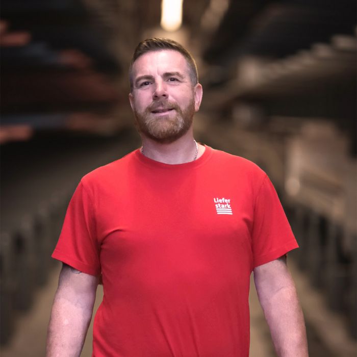 Stark AG Mitarbeiter Mann im roten T-Shirt von Stark AG in Holzlager.
